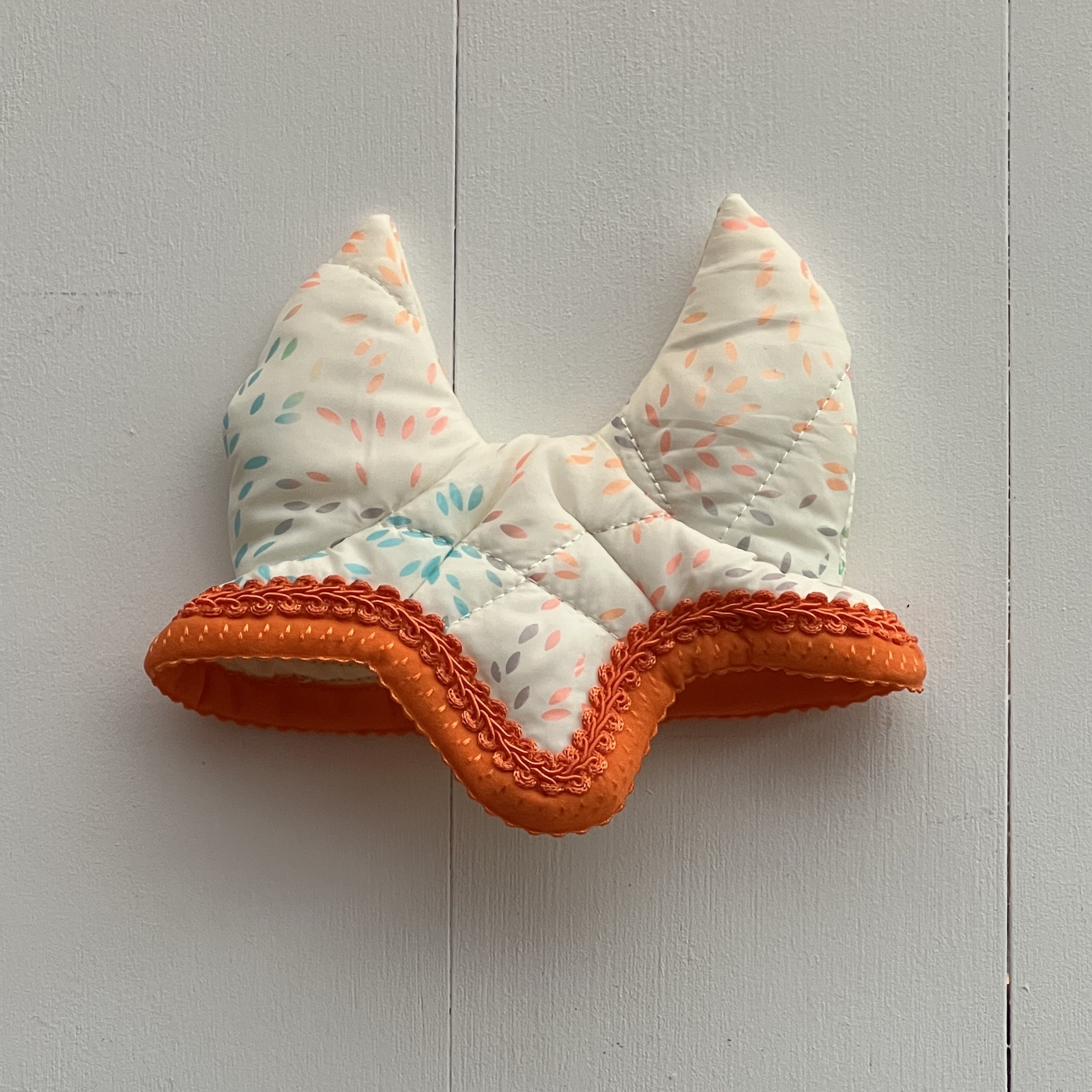 Oornetje creme met gekleurde figuurtjes bies oranje en oranje bandje