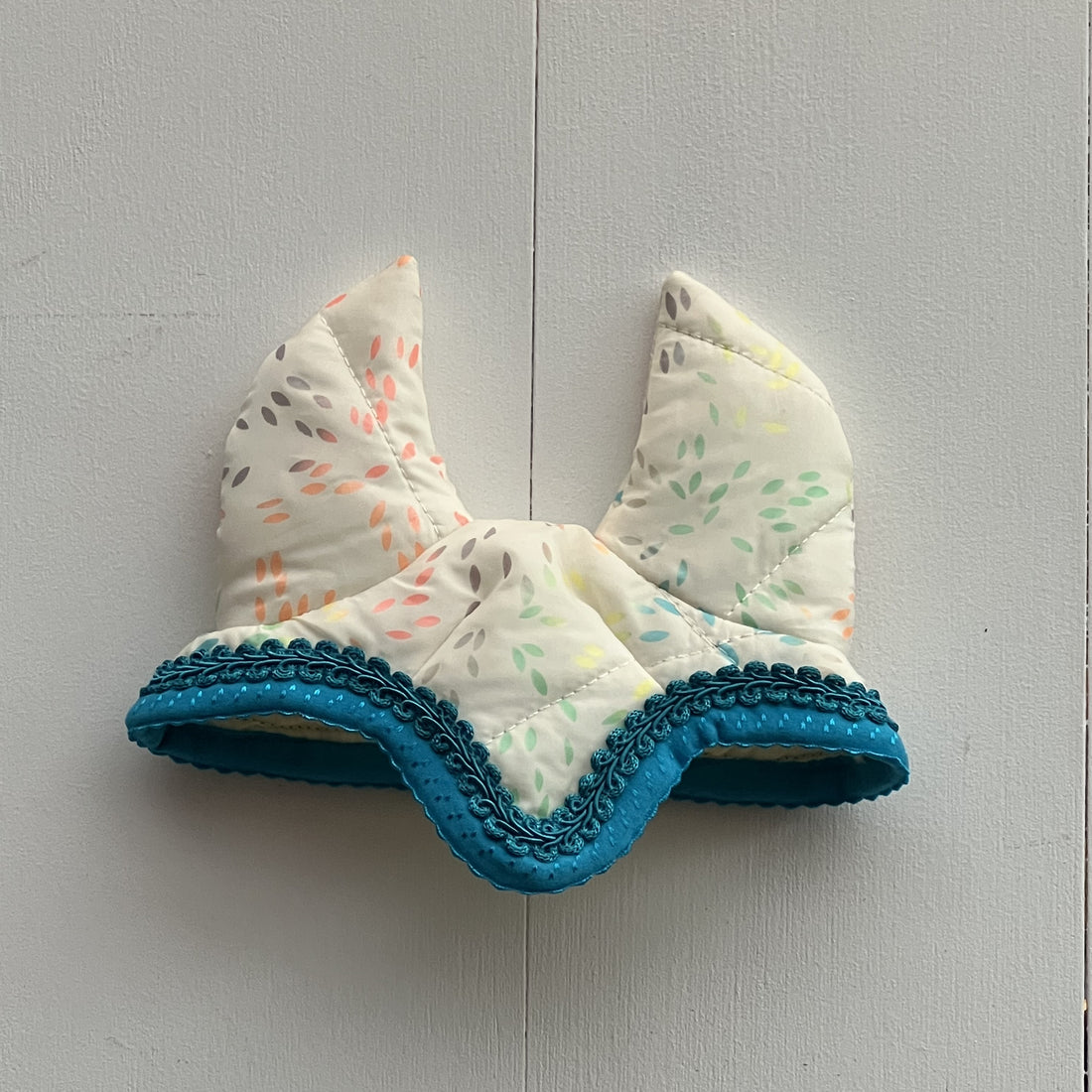 Oornetje creme met gekleurde figuurtjes bies blauw en blauw bandje